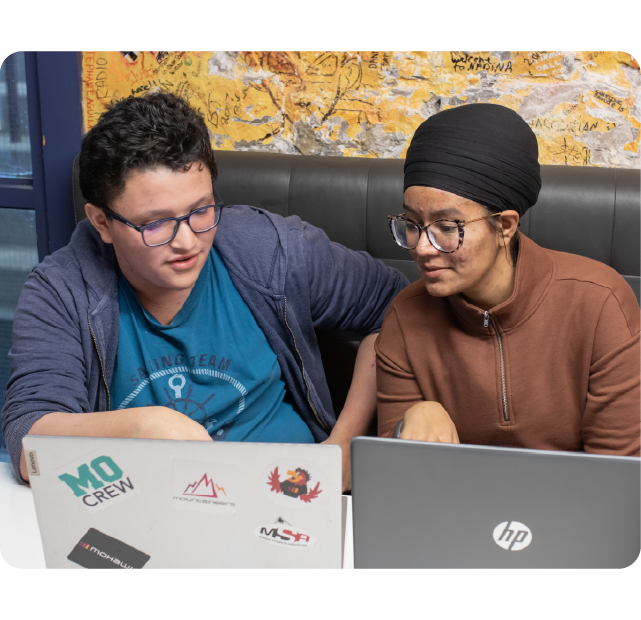 Students talking while working on their laptops.