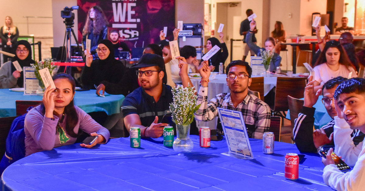 Group of students raising their voting cards at The 2023 AMM. 